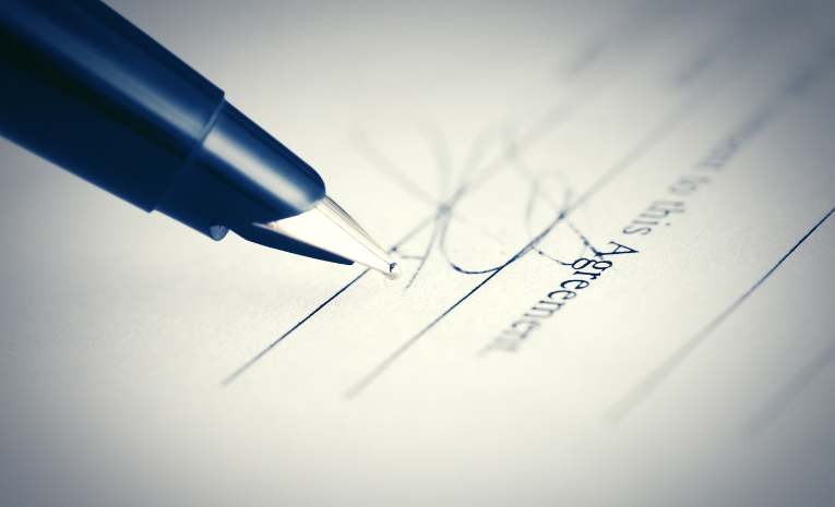 Contratos Comerciales: Imagen de la parte final de un contrato, con la firma realizada con una pluma.