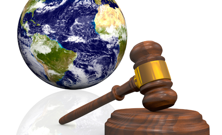 Derecho Internacional: Imagen de la Tierra con un mazo de juez de madera en primer plano.