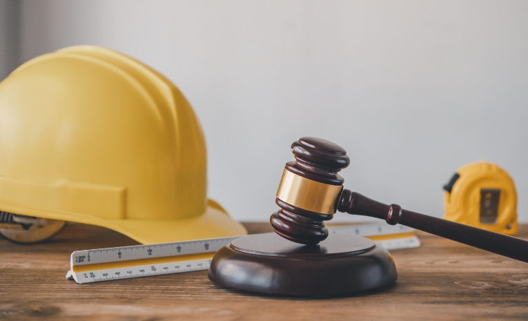 Derecho Laboral: Imagen con un metro, casco amarillo, escalímetro y un mazo de juez de madera.