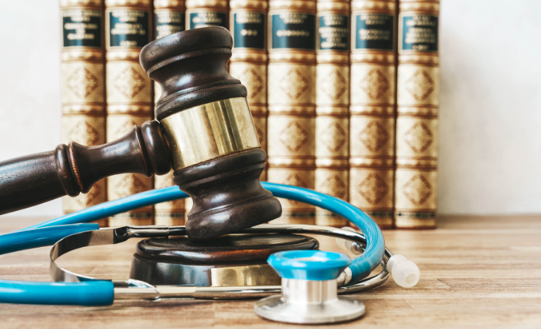 Derecho de la Salud: Imagen de un mazo de madera rodeado por un estetoscopio, con nueve libros de leyes en segundo plano.