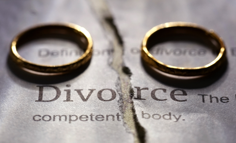 Divorcio representado por dos anillos separados y un documento legal rasgado.