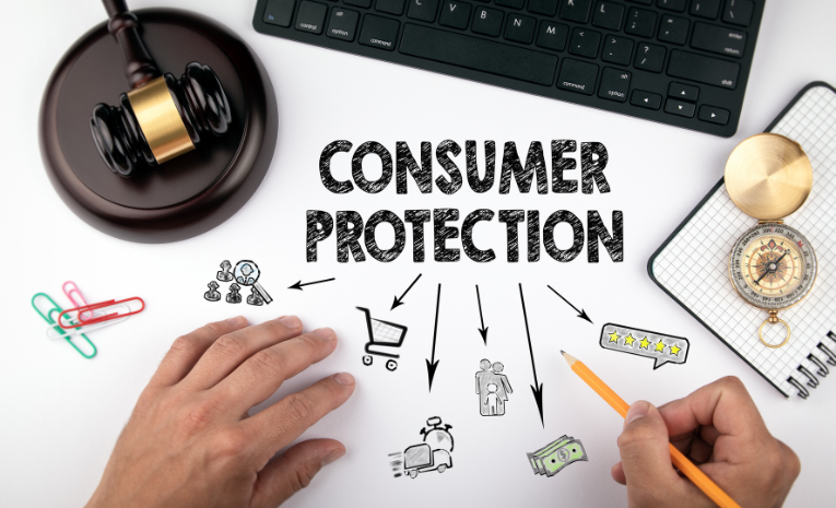 Protección del Consumidor: Imagen con mazo de madera, teclado, blog de notas, brújula, y el texto 'consumer protection' con flechas y mini dibujos.