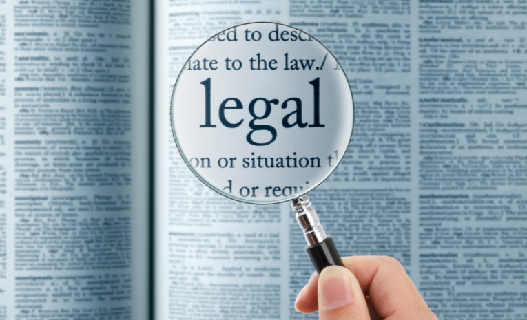 Lupa enfocando la palabra 'legal' en un texto impreso, simbolizando la búsqueda de interpretación legal