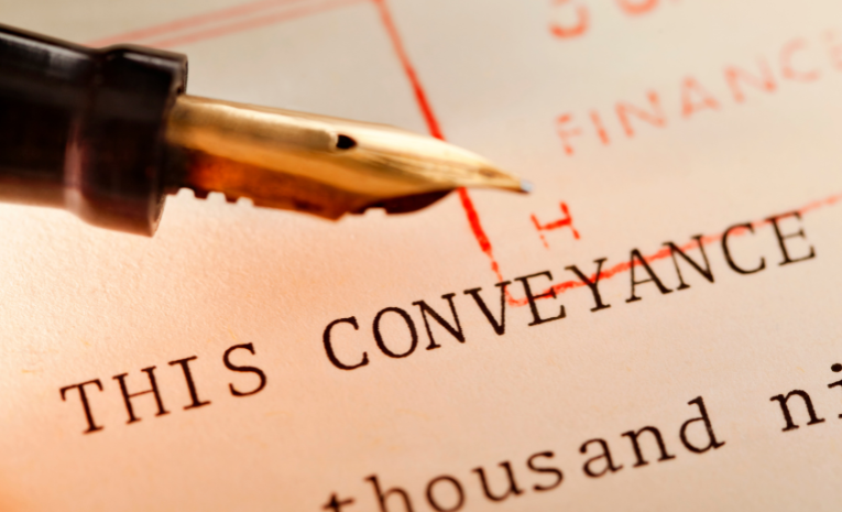 Pluma fuente sobre un documento marcado con el término 'CONVEYANCE' destacando aspectos financieros y legales